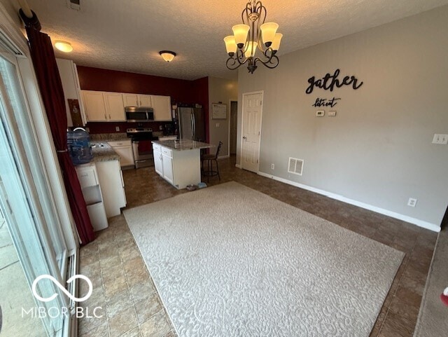 1711 Jaques Dr, Lebanon, IN 46052 - kitchen featuring appliances with stainless steel finishes, white cabinets, a chandelier, hanging light fixtures, and a center island