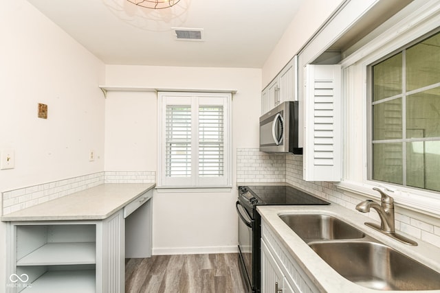 713 W Cromer Ave, Muncie, IN 47303 - kitchen with black electric range oven, stainless steel microwave, light wood-type flooring, decorative backsplash, and white cabinets
