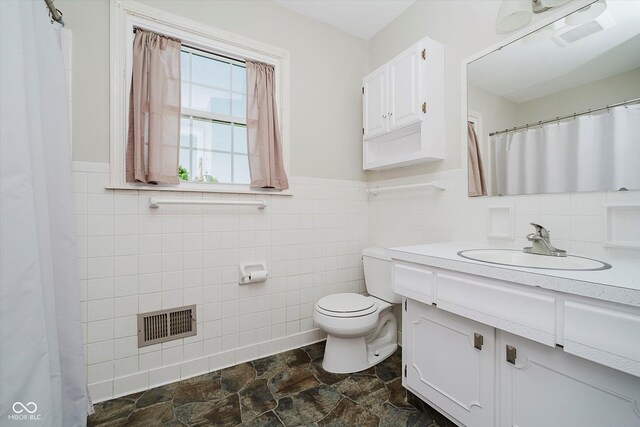 6146 Rucker Rd, Indianapolis, IN 46220 - full bathroom with tile walls, vanity, wainscoting, and stone finish floors