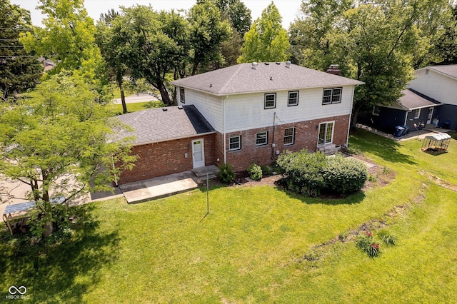 6146 Rucker Rd, Indianapolis, IN 46220 - back of house featuring brick siding, a yard, a chimney, and roof with shingles