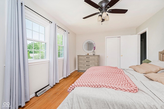 6146 Rucker Rd, Indianapolis, IN 46220 - bedroom featuring light wood-style flooring, a closet, ceiling fan, and a baseboard heating unit