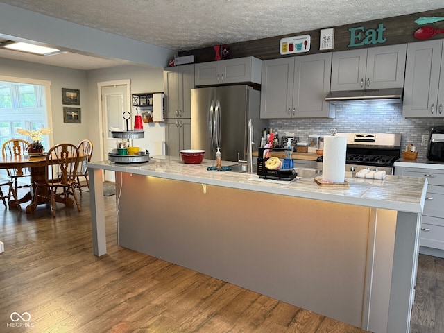 75 Byram Blvd, Martinsville, IN 46151 - kitchen with appliances with stainless steel finishes, under cabinet range hood, a textured ceiling, light countertops, and dark wood finished floors