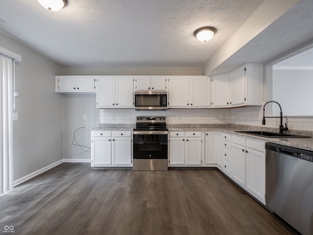 3734 Lacebark Dr, Indianapolis, IN 46235 - kitchen with stainless steel appliances, a sink, baseboards, a textured ceiling, and dark wood-style flooring