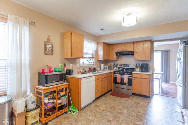 8056 Maple Stream Blvd, Indianapolis, IN 46217 - kitchen featuring stainless steel appliances, under cabinet range hood, light countertops, a sink, and a textured ceiling