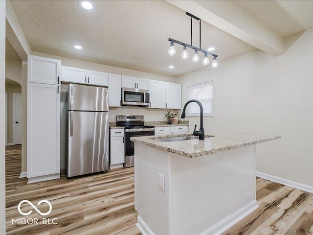 3558 N Gladstone Ave, Indianapolis, IN 46218 - kitchen featuring appliances with stainless steel finishes, light wood finished floors, a sink, white cabinetry, and light stone counters