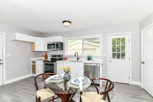 1820 Hemlock Ln, Plainfield, IN 46168 - kitchen with stainless steel appliances, a sink, light countertops, light wood finished floors, and white cabinetry