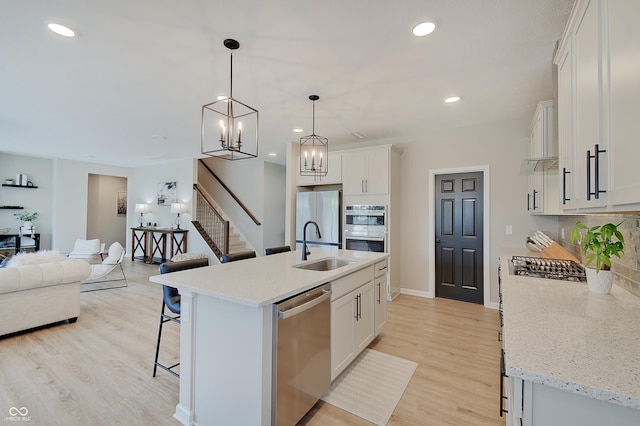 4163 Ironclad Dr, Bargersville, IN 46106 - kitchen featuring appliances with stainless steel finishes, a kitchen bar, open floor plan, backsplash, and light wood-style floors