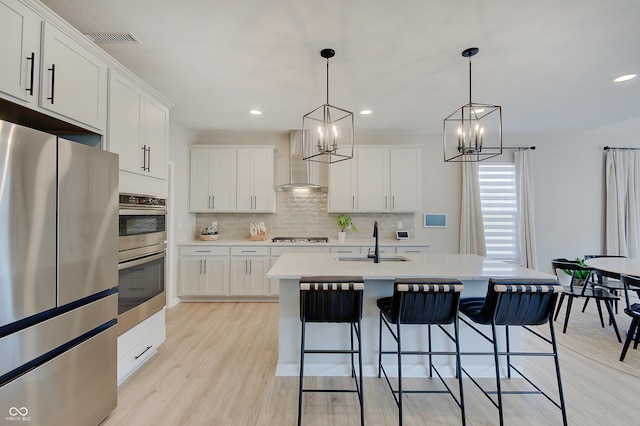 4163 Ironclad Dr, Bargersville, IN 46106 - kitchen with appliances with stainless steel finishes, wall chimney exhaust hood, a chandelier, decorative backsplash, and light wood finished floors