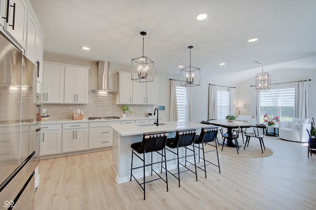 4163 Ironclad Dr, Bargersville, IN 46106 - kitchen featuring wall chimney exhaust hood, stainless steel appliances, a chandelier, light wood-style floors, and light countertops