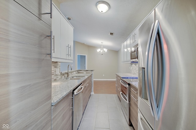 1074 Timber Creek Dr Unit 8, Carmel, IN 46032 - kitchen with appliances with stainless steel finishes, a sink, backsplash, a chandelier, and light tile patterned floors