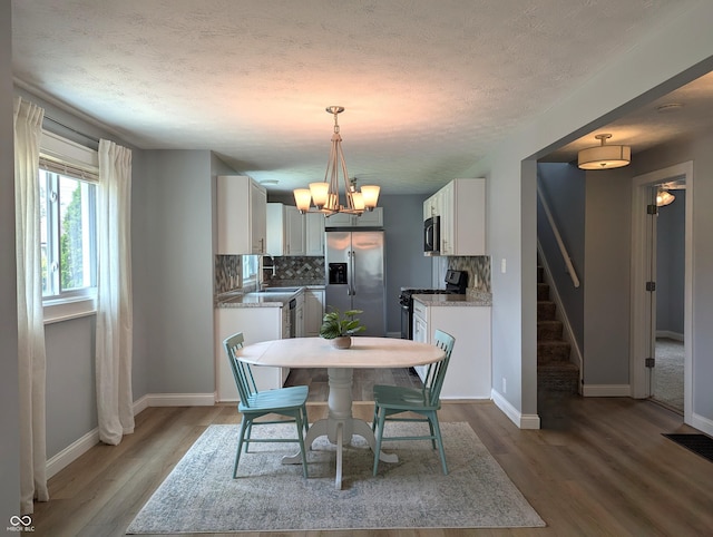1637 Meridian St, Columbus, IN 47201 - dining space featuring stairway, wood finished floors, a chandelier, baseboards, and a textured ceiling