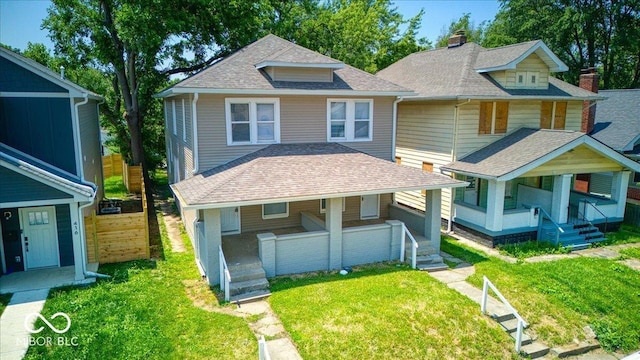 418 Eastern Ave, Indianapolis, IN 46201 - view of front facade with covered porch, roof with shingles, a front yard, and a chimney