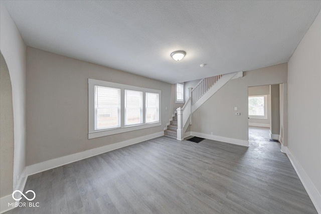 418 Eastern Ave, Indianapolis, IN 46201 - unfurnished living room featuring wood finished floors, stairway, a textured ceiling, and arched walkways