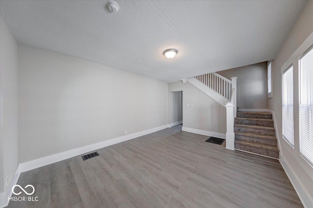 420 Eastern Ave, Indianapolis, IN 46201 - unfurnished living room featuring stairway, wood finished floors, plenty of natural light, and a textured ceiling
