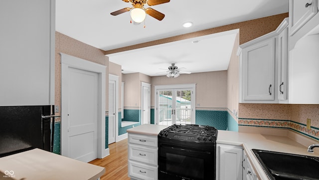 753 Walnut St, Franklin, IN 46131 - kitchen featuring ceiling fan, black range with gas cooktop, wallpapered walls, white cabinets, and light wood-style flooring
