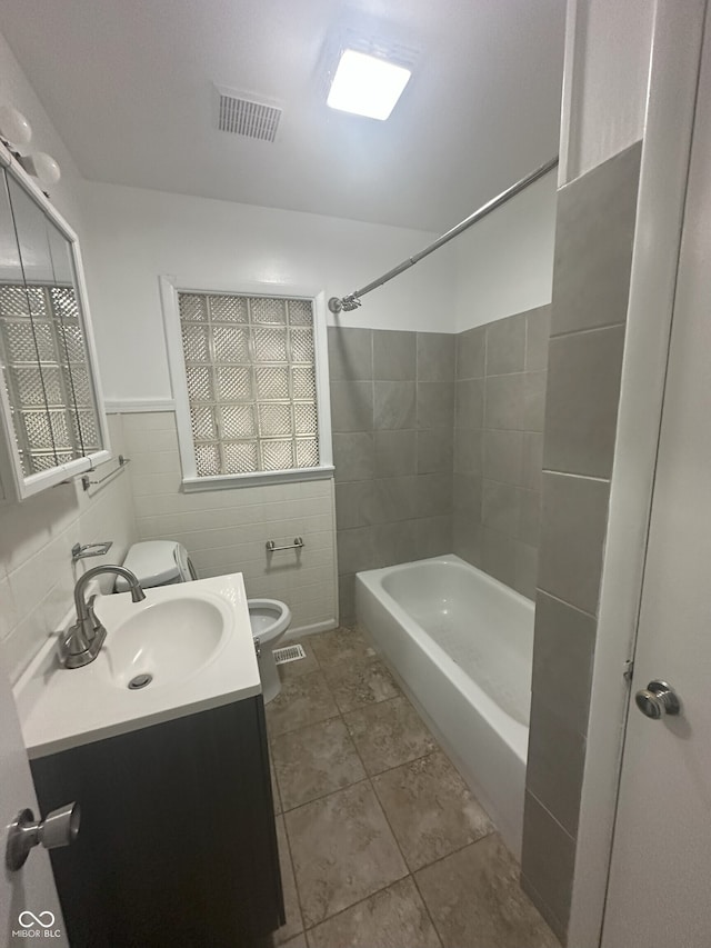 2180 N Irwin St, Indianapolis, IN 46219 - bathroom featuring tile walls, toilet, vanity, shower / washtub combination, and tile patterned floors