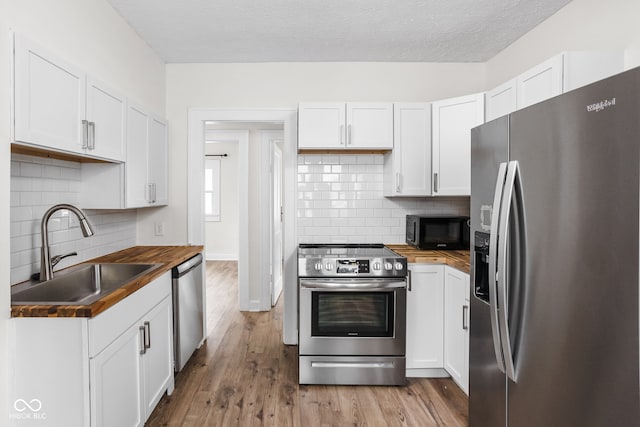 614 N Drexel Ave, Indianapolis, IN 46201 - kitchen featuring stainless steel appliances, wooden counters, a sink, wood finished floors, and a textured ceiling