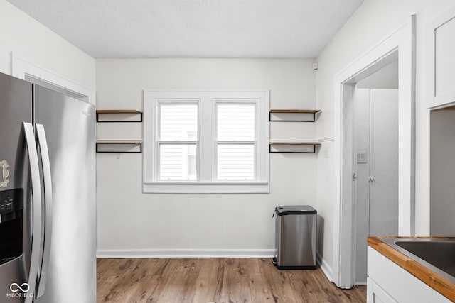 614 N Drexel Ave, Indianapolis, IN 46201 - kitchen featuring stainless steel fridge, white cabinetry, baseboards, light wood-style flooring, and wood counters