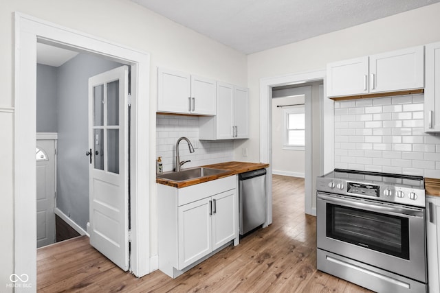 614 N Drexel Ave, Indianapolis, IN 46201 - kitchen with appliances with stainless steel finishes, a sink, white cabinetry, backsplash, and butcher block counters