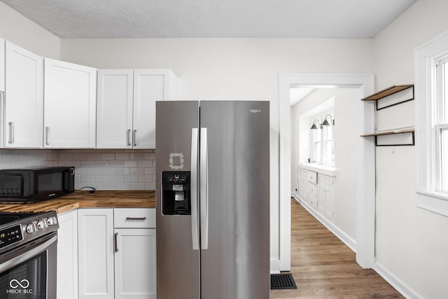 614 N Drexel Ave, Indianapolis, IN 46201 - kitchen featuring stainless steel appliances, butcher block countertops, light wood-style floors, tasteful backsplash, and white cabinets