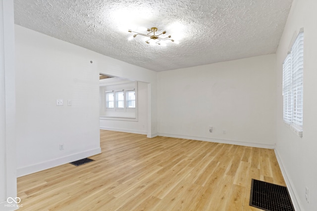 909 N Parker Ave, Indianapolis, IN 46201 - empty room featuring a textured ceiling, light wood-style flooring, baseboards, and a chandelier