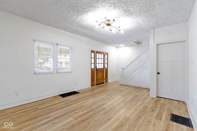 909 N Parker Ave, Indianapolis, IN 46201 - entryway with stairway, light wood-style floors, a textured ceiling, and baseboards