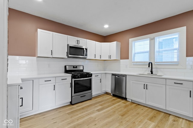 909 N Parker Ave, Indianapolis, IN 46201 - kitchen with appliances with stainless steel finishes, a sink, light wood finished floors, tasteful backsplash, and white cabinetry