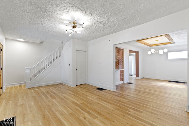 909 N Parker Ave, Indianapolis, IN 46201 - unfurnished living room featuring light wood-style floors, stairs, a textured ceiling, baseboards, and a chandelier