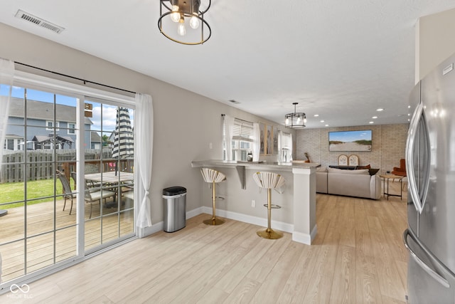 2580 Bluewood Way, Plainfield, IN 46168 - kitchen with freestanding refrigerator, light wood finished floors, a breakfast bar, open floor plan, and hanging light fixtures