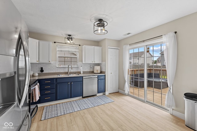 2580 Bluewood Way, Plainfield, IN 46168 - kitchen with stainless steel appliances, blue cabinets, white cabinets, decorative backsplash, and light wood-style floors