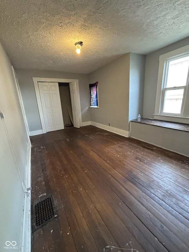 18 E Church St, Brazil, IN 47834 - unfurnished bedroom with wood-type flooring, a textured ceiling, baseboards, and a closet