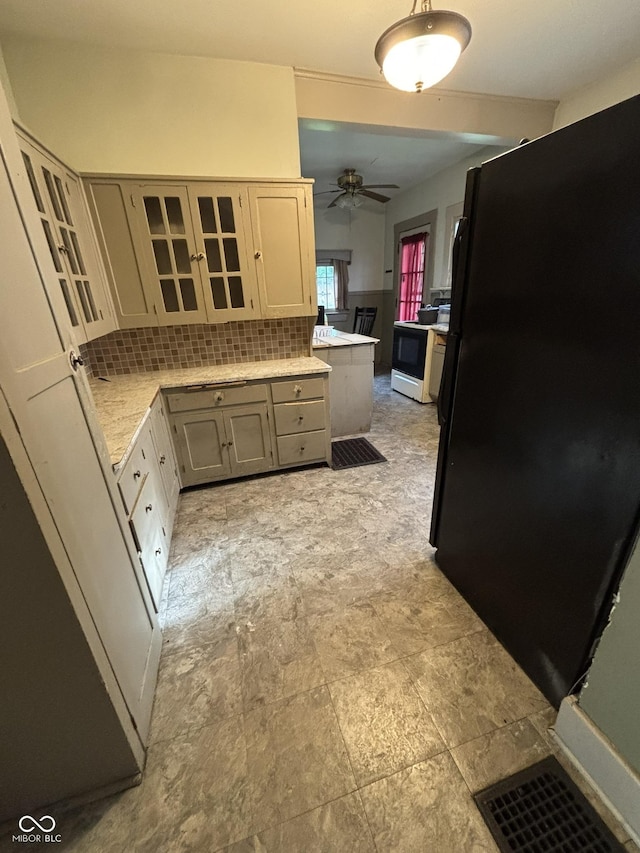 18 E Church St, Brazil, IN 47834 - kitchen featuring freestanding refrigerator, backsplash, light countertops, a ceiling fan, and glass insert cabinets