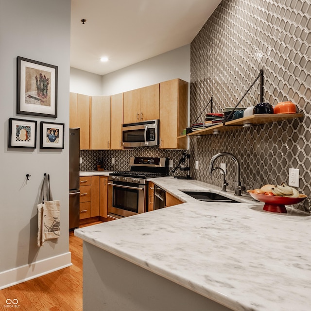 611 N Park Ave Unit 104, Indianapolis, IN 46204 - kitchen with stainless steel appliances, a sink, light wood finished floors, decorative backsplash, and baseboards