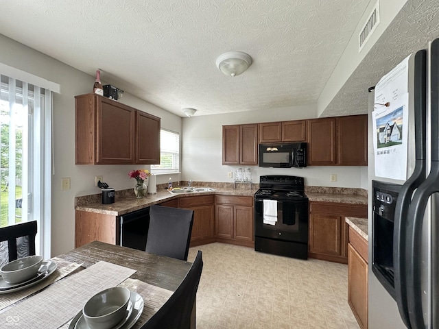 4925 Chip Shot Ln, Indianapolis, IN 46235 - kitchen with black appliances, a sink, a textured ceiling, brown cabinetry, and light floors