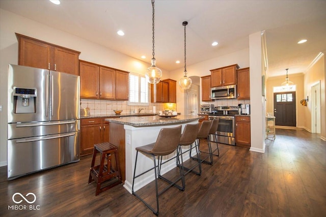 12976 Walbeck Dr, Fishers, IN 46037 - kitchen featuring appliances with stainless steel finishes, brown cabinets, a kitchen bar, decorative backsplash, and recessed lighting