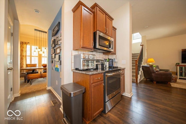 12976 Walbeck Dr, Fishers, IN 46037 - kitchen featuring stainless steel appliances, open floor plan, brown cabinetry, and dark wood-style flooring