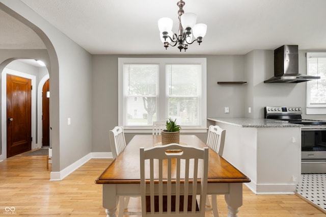 110 E Harrison St, Spiceland, IN 47346 - dining area with arched walkways, light wood finished floors, and a chandelier