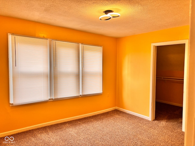 624 N Rural St, Indianapolis, IN 46201 - unfurnished bedroom with a textured ceiling, carpet, baseboards, and a spacious closet