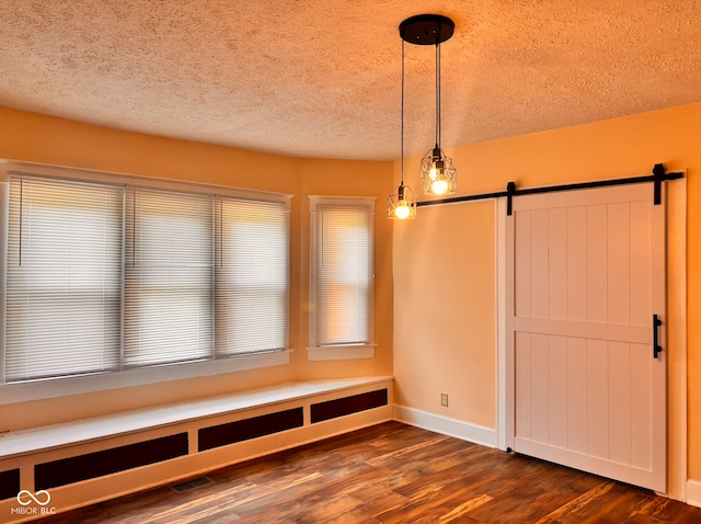 624 N Rural St, Indianapolis, IN 46201 - unfurnished dining area featuring dark wood-style floors, a barn door, baseboards, and a textured ceiling