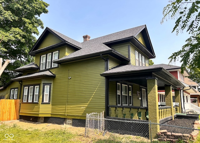 624 N Rural St, Indianapolis, IN 46201 - view of side of property featuring covered porch, a chimney, and a shingled roof