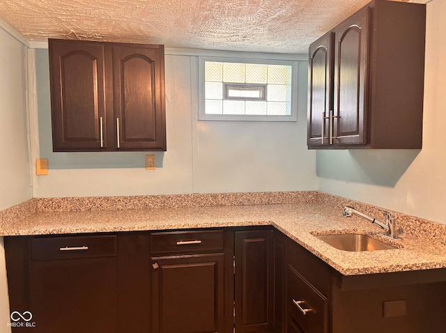 624 N Rural St, Indianapolis, IN 46201 - kitchen with a sink, a textured ceiling, dark brown cabinetry, and light stone counters