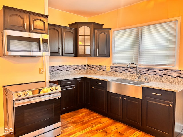 624 N Rural St, Indianapolis, IN 46201 - kitchen featuring appliances with stainless steel finishes, a sink, light wood-style flooring, light stone counters, and decorative backsplash