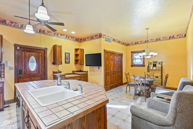 239 E 11th St, Indianapolis, IN 46202 - kitchen with tile countertops, a sink, a chandelier, ceiling fan, and light flooring