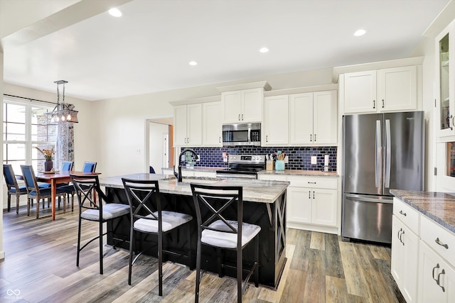 3301 N 200 W, Franklin, IN 46131 - kitchen with appliances with stainless steel finishes, a breakfast bar area, light wood-style floors, an island with sink, and decorative backsplash