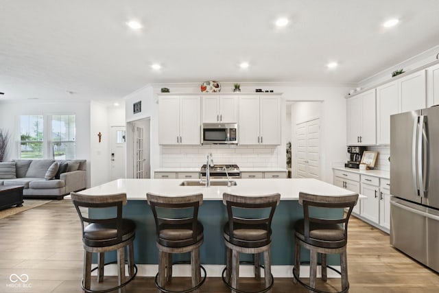 11429 Lottie Cir, Noblesville, IN 46060 - kitchen featuring appliances with stainless steel finishes, a sink, light countertops, a kitchen breakfast bar, and recessed lighting