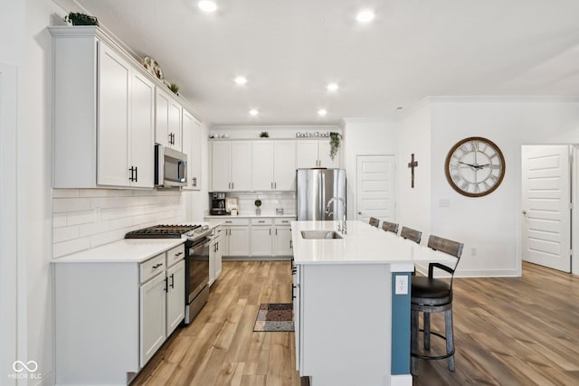 11429 Lottie Cir, Noblesville, IN 46060 - kitchen featuring appliances with stainless steel finishes, a sink, a kitchen bar, light wood-style flooring, and tasteful backsplash