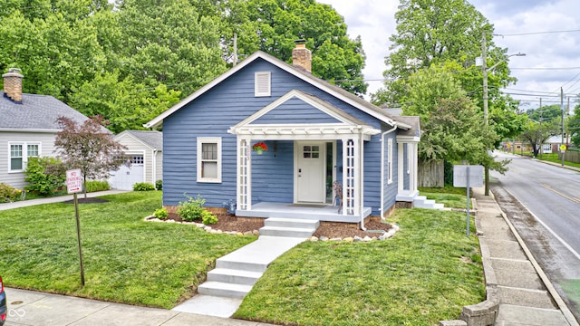 5203 Carrollton Ave, Indianapolis, IN 46220 - bungalow featuring covered porch, a chimney, a front lawn, and an outdoor structure