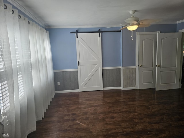 1317 S Ebert Dr, Rockville, IN 47872 - unfurnished bedroom featuring wainscoting, wood finished floors, ornamental molding, a barn door, and ceiling fan