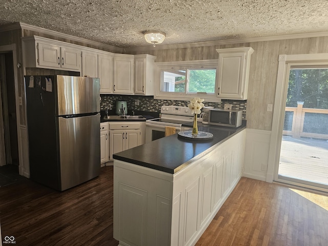 1317 S Ebert Dr, Rockville, IN 47872 - kitchen featuring stainless steel appliances, dark countertops, ornamental molding, a peninsula, and dark wood-style flooring