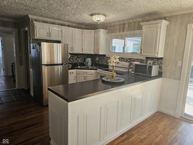 1317 S Ebert Dr, Rockville, IN 47872 - kitchen with appliances with stainless steel finishes, dark countertops, dark wood-type flooring, ornamental molding, and a peninsula